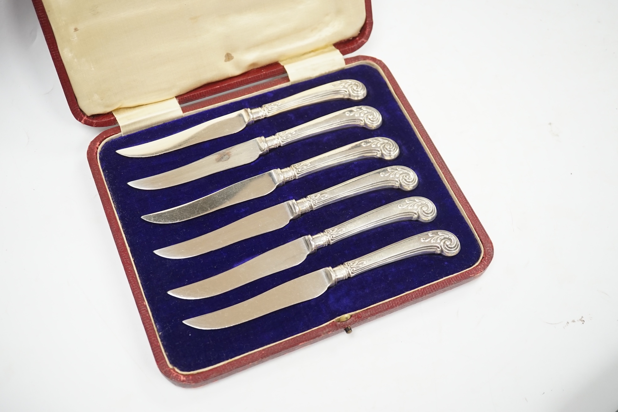 A cased set of six George V silver teaspoons, two cased sets of six silver handled tea knives, fourteen assorted items of 19th century and later silver spoons and a pair of silver sugar tongs. Condition - fair to good